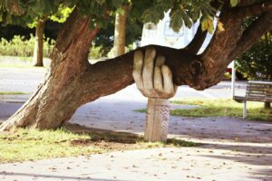 statue of hand supporting a live tree to depict sentiment of supporting growth and life in community